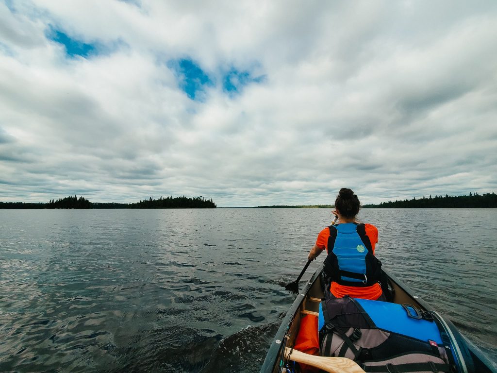 Women wearing a paddling life jacket and holding a paddle in a canoe while canoe camping on the Missinaibi River.