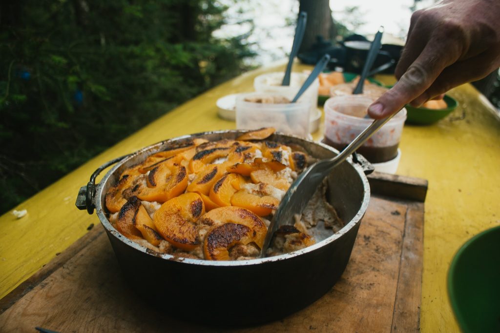 Dutch oven resting on a yellow canoe with french toast inside