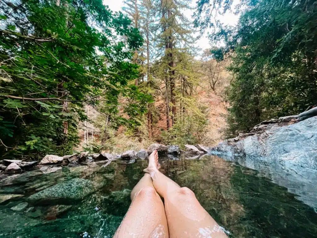 Legs sitting in a Sykes Hot Springs pool on the Pine Ridge Trail near Big Sur