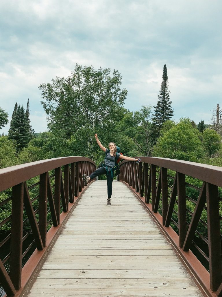 Mikaela jumping for joy on the bridge over Oxtongue River on the Western Uplands Backpacking Trail in Algonquin Provincial Park