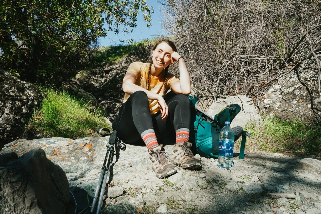 Woman sitting on a rock on the Ohlone Wilderness Trail with her backpacking gear